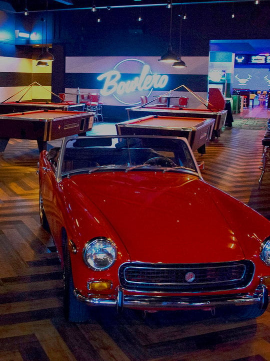 Retro red car with red billiards tables behind it