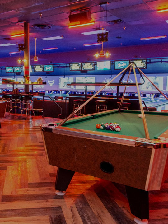 Green billiards table with seating area and lanes in the background