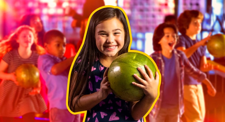 Smiling kid getting ready to roll a bowling ball with four other kids in the background