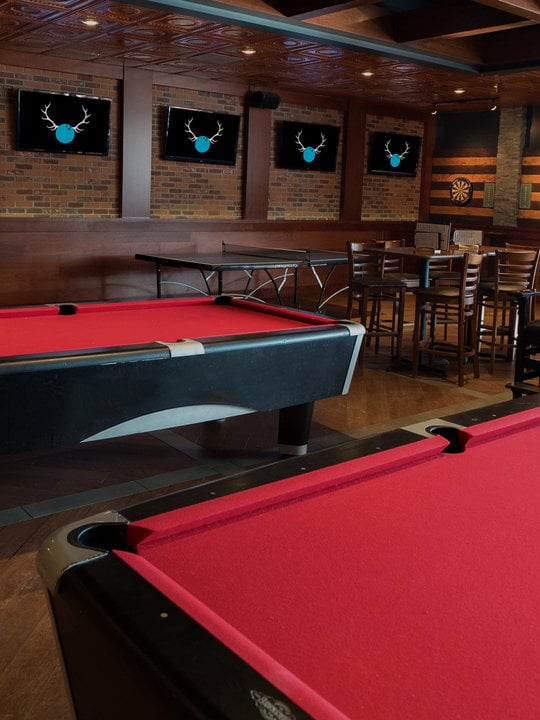 Red billiards tables with darts in the background
