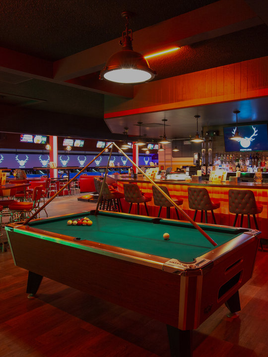 Green billiards table with bar area and lanes in the background