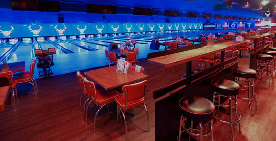 view of bowling lanes lit blue from the seating area