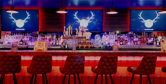 view of neon lit bar with tv screens