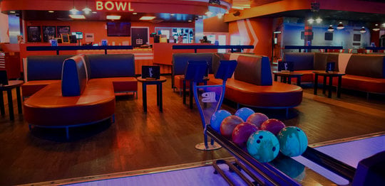 Ball return with bowling balls and a lounge seating area
