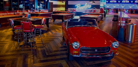 Retro red car with red billiards tables behind it