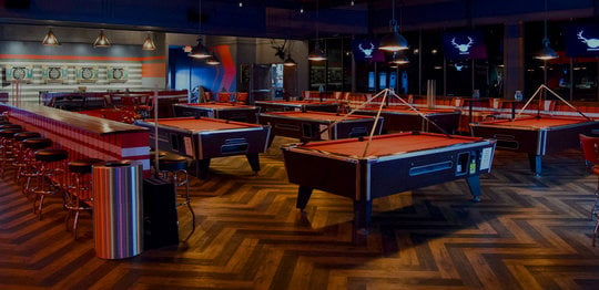 Multiple red billiards tables with darts in the background