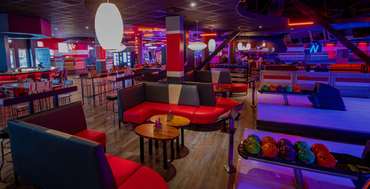 bowling ball racks, booths, and a bar area in a bowling alley