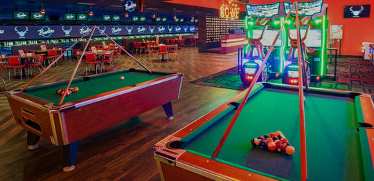 Green billiards table with seating area and lanes in the background