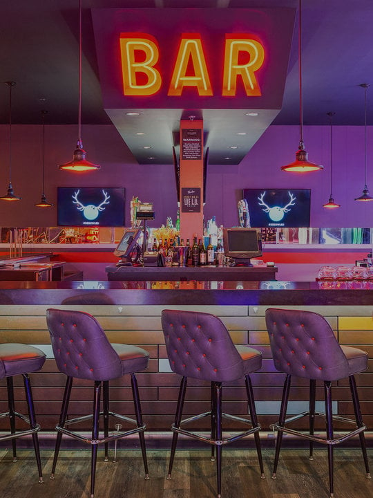bar stools, a bar, and an orange neon 'bar' sign