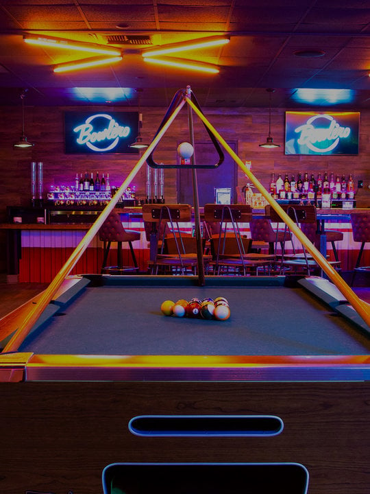 Green billiards table with a bar area behind it