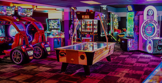 neon lit arcade games and air hockey table