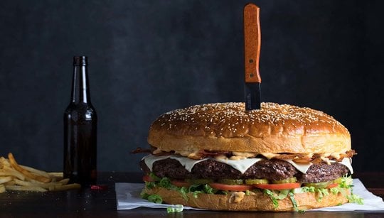 Behemoth Burger with Knife, Beer Bottle and Fries to the Side