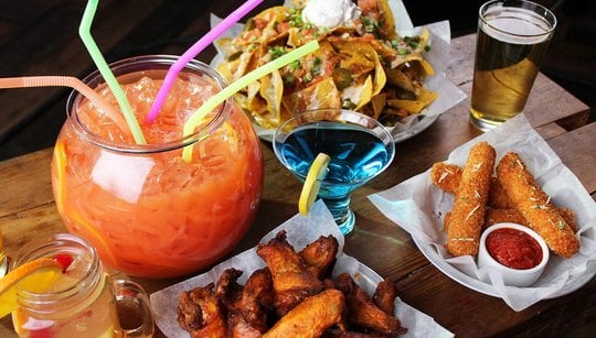 drink in a fish bowl, nachos, mozzarella sticks, chicken wings and several other cocktails and beer
