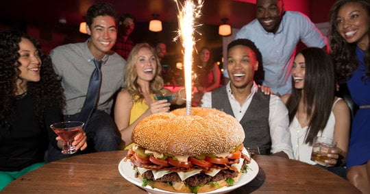 friends crowded around a giant burger with sparklers shooting out of it