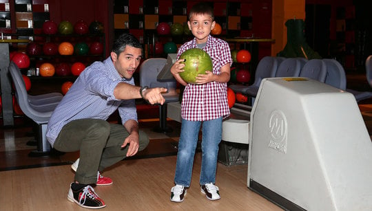 Dad showing son how to bowl