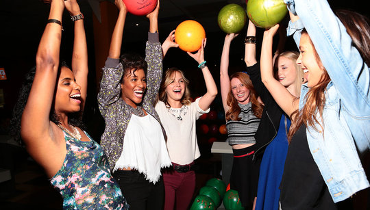 girls holding up bowling balls over their heads