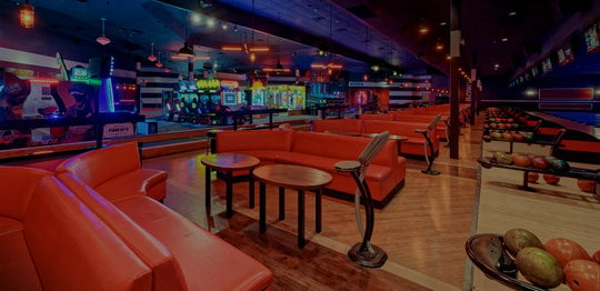 Bowling lanes with red plush couches and arcade in background