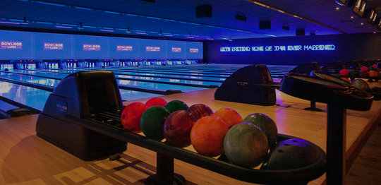 bowing lanes and ball returns with neon signage on wall