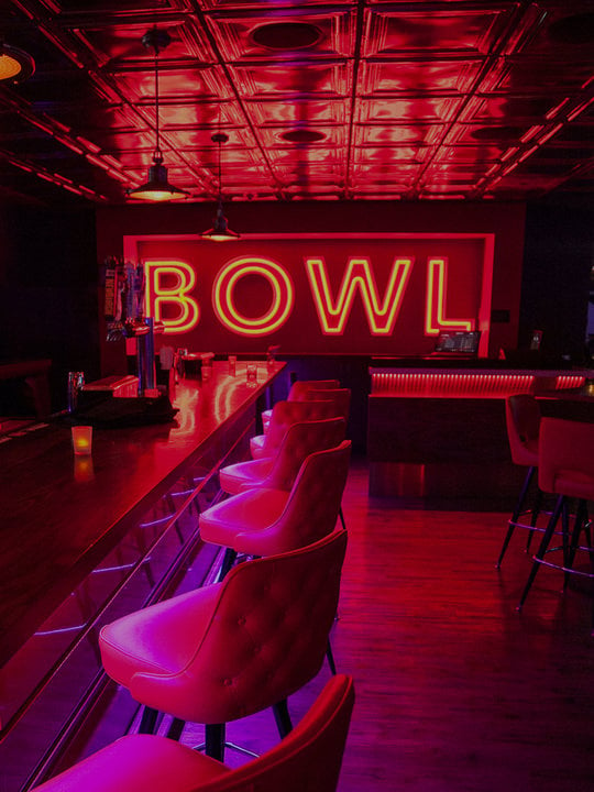 bar area with neon BOWL sign on wall