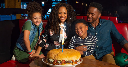 family sitting in front of a gigantic burger