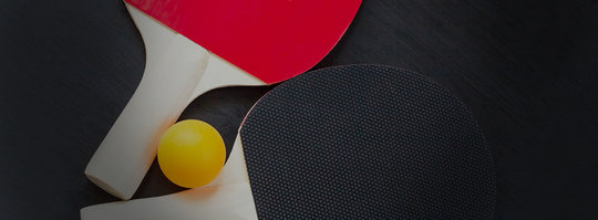 two ping pong paddles and a ball